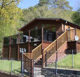 A wooden lodge with a deck and stairs at High View Lodge White Cross Bay near Troutbeck Bridge
