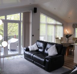 A living room with a sofa and a dining table at High View Lodge White Cross Bay near Troutbeck Bridge