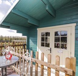 A small fenced porch with a round table and two chairs outside double cream doors at The Nook Royal Wootton Bassett