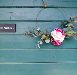 A door with a floral wreath and a sign reading THE NOOK at The Nook in Royal Wootton Bassett