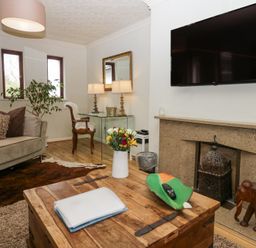 A living room with a wooden coffee table a sofa and a wall mounted TV at Sandown in Bowness-on-Windermere
