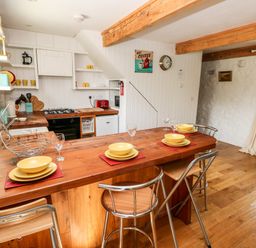 A kitchen with wooden countertops a wooden dining table set with yellow dishes and metal chairs at Beekeeper's Cottage in Pembroke