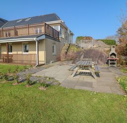 A house with a patio table and benches on a paved area next to a barbecue grill in a garden at Bluebell House and Gardens in Gurteenulla near Ballydehob County Cork