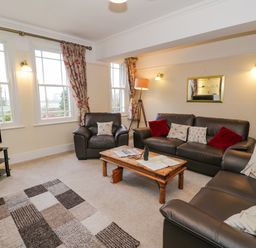 A living room with leather sofas a wooden coffee table a floor lamp and a television at The Farm House in Bala
