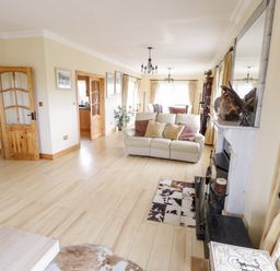 A living room with a white sofa and pillows a fireplace and wooden doors at Shraigh Beach in Belmullet County Mayo