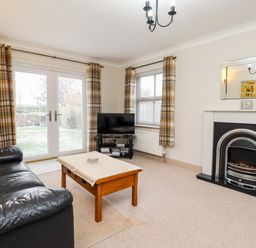A living room with a black leather sofa and wooden coffee table near a fireplace and TV at Darling Cottage in Bamburgh