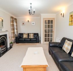 A living room with two black leather sofas a wooden coffee table a fireplace and wall art at Darling Cottage in Bamburgh