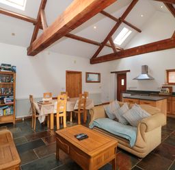 A living room with a television and dining area at Riverside Barn in Gilwern near Crickhowell and Abergavenny