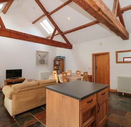 A living room with a sofa and television at Riverside Barn in Gilwern near Crickhowell and Abergavenny