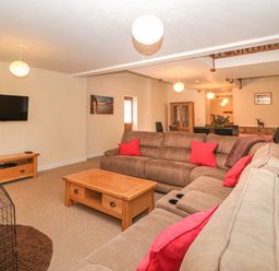 A living room with sectional sofas red cushions wooden coffee table and a wall-mounted tv at The Old Barn in Harman's Cross near Swanage