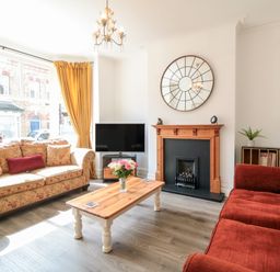 A living room with two sofas a coffee table a fireplace a TV and a large window with curtains at The Robins in Filey