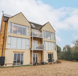A three-story building with large windows and balconies surrounded by trees at Beautiful Cotswold View in Bourton-On-The-Water