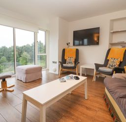 A living room with chairs a sofa a coffee table and large windows showing trees at Beautiful Cotswold View in Bourton-On-The-Water