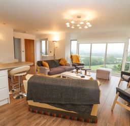 A living room with sofas armchairs and large windows overlooking greenery at Beautiful Cotswold View in Bourton-On-The-Water