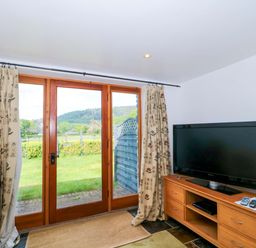 A living room with a TV and windows at Longside in Gilwern