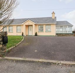 A one-story house with a driveway and a lawn surrounded by a stone wall at Raheen in Castletownshend County Cork