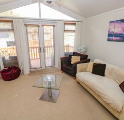 A living room with a sofa armchair glass coffee table and wall art at Cladebrine Wisemans Bridge near Saundersfoot