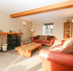 A living room with two sofas a wooden coffee table and a brick fireplace at Ty Top in Llanfaethlu