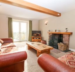 A living room with sofas a wooden coffee table a fireplace and a television at Ty Top in Llanfaethlu
