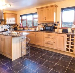 A kitchen with wooden cabinets a center island and tiled floor at Tynddol Bungalow Llanbadarn-Fynydd near Llanbister
