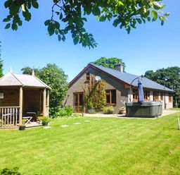 A bungalow with a wooden gazebo and inflatable hot tub in a garden at Tynddol Bungalow in Llanbadarn-Fynydd near Llanbister