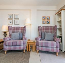 Two plaid armchairs with gray pillows between two wooden side tables and lamps in a living room at 37 Ocean Park in Westward Ho