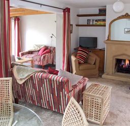 A living room with striped sofas a fireplace shelves and a television at Hour Cottage in Stow on the Wold