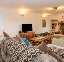 A living room with sofas wooden coffee table television and a fireplace at East Farm House in Humshaugh near Hexham