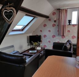 A sitting area with two black armchairs a coffee table a television and floral wallpaper at The Coach House in North Newton near Bridgwater