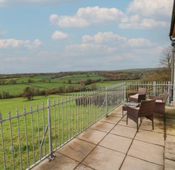 An outdoor area with chairs and a table overlooking fields at Bwthyn-y-Rhiw in Penybanc near Llandeilo