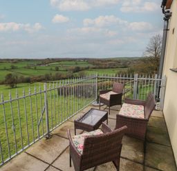 A balcony with seating and a table overlooking fields at Bwthyn-y-Rhiw in Penybanc near Llandeilo
