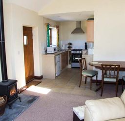 A kitchen and dining area with a wood stove and a beige sofa at Dovetail in Westbury-on-Severn