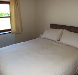 A bedroom with a double bed and pillows next to a window with curtains at Dovetail in Westbury-on-Severn
