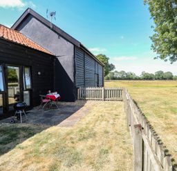 An outdoor area with a table and chairs near a house at Tawny Owl Barn Shipdham near Dereham