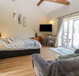 A bedroom featuring a bed with cushions and a table with chairs at Tawny Owl Barn Shipdham near Dereham