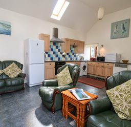 A kitchen and seating area with green leather chairs and wooden cabinets at Yr Hen Ysgubor in Trelech near St Clears