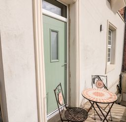 An outdoor area with a green door a small round table and two chairs with tiled tops at Nutshell in Whitby