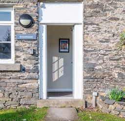 Stone exterior wall with an open doorway and window at Greenhowes Graythwaite near Hawkshead