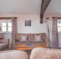 A living room with sofas cushions wooden coffee table and patterned curtains at Lords Leap Graythwaite near Hawkshead