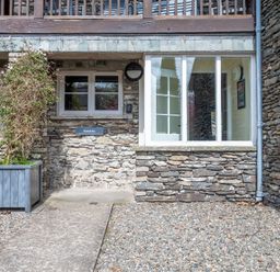 Stone building exterior with windows wooden planter and gravel ground at Bassicks in Hawkshead