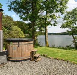 A hot tub with a wooden structure beside a lake at Hullet Hall at the Graythwaite Estate near Hawkshead