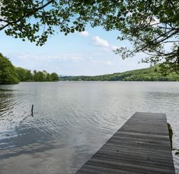 A lake view with a dock and trees at Hullet Hall at the Graythwaite Estate near Hawkshead