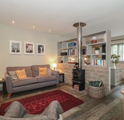 A living room with a sofa and wood stove at The Stable in Deepdean near Ross-on-Wye