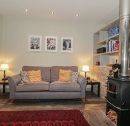 A living room with a sofa, lamp, and stove at The Stable in Deepdean near Ross-on-Wye