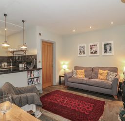 A living room with a sofa and kitchen area at The Stable in Deepdean near Ross-on-Wye