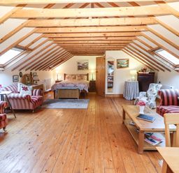 A loft bedroom with wooden beams striped sofas and a bed at Mrs Delaney's Loft in Ardfinnan near Clonmel County Tipperary