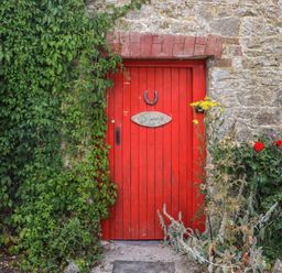 A red door with a sign and flowers at Mrs Delaney's Loft Ardfinnan near Clonmel County Tipperary
