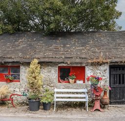 A stone wall with red windows and potted plants at Mrs Delaney's Loft in Ardfinnan near Clonmel, County Tipperary