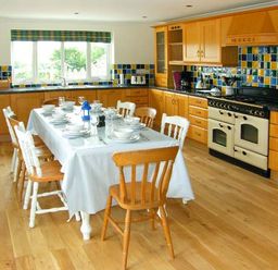 A kitchen with a dining table set for a meal and wooden cabinets at The Grange in Little Haven near Haverfordwest 