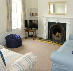 A living room with sofas a bean bag a fireplace and a television at The Grange in Little Haven near Haverfordwest 